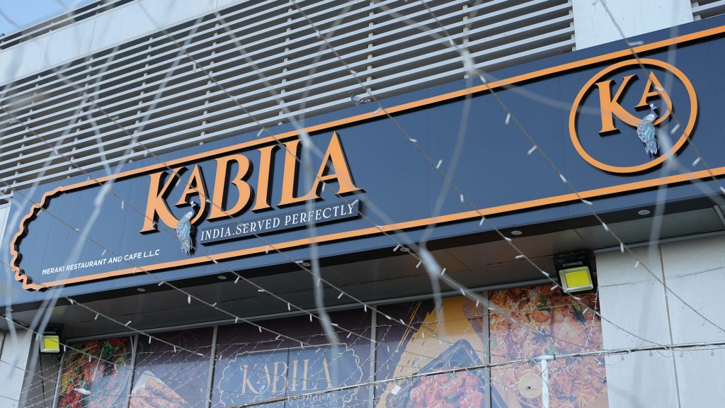 The exterior sign of "Kabila," a restaurant offering Indian cuisine, with the slogan "India. Served Perfectly."